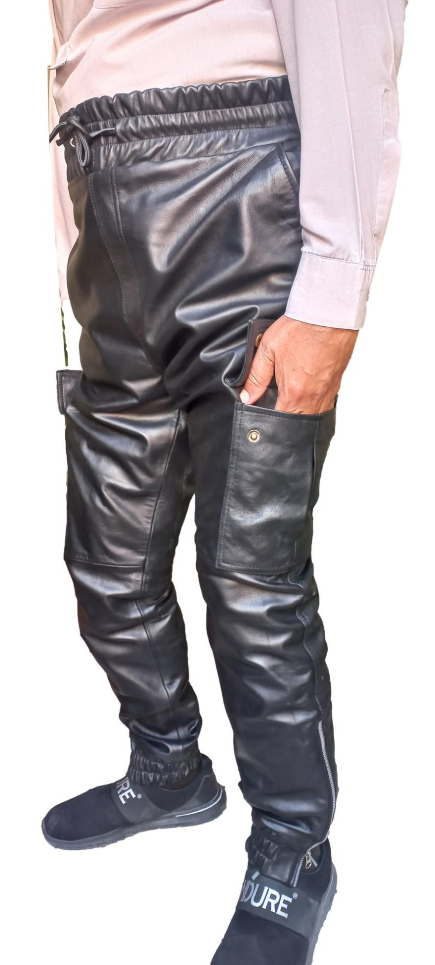 Picture of a model wearing our Black Leather Cargo Pants, side view with hands in thigh pockets.