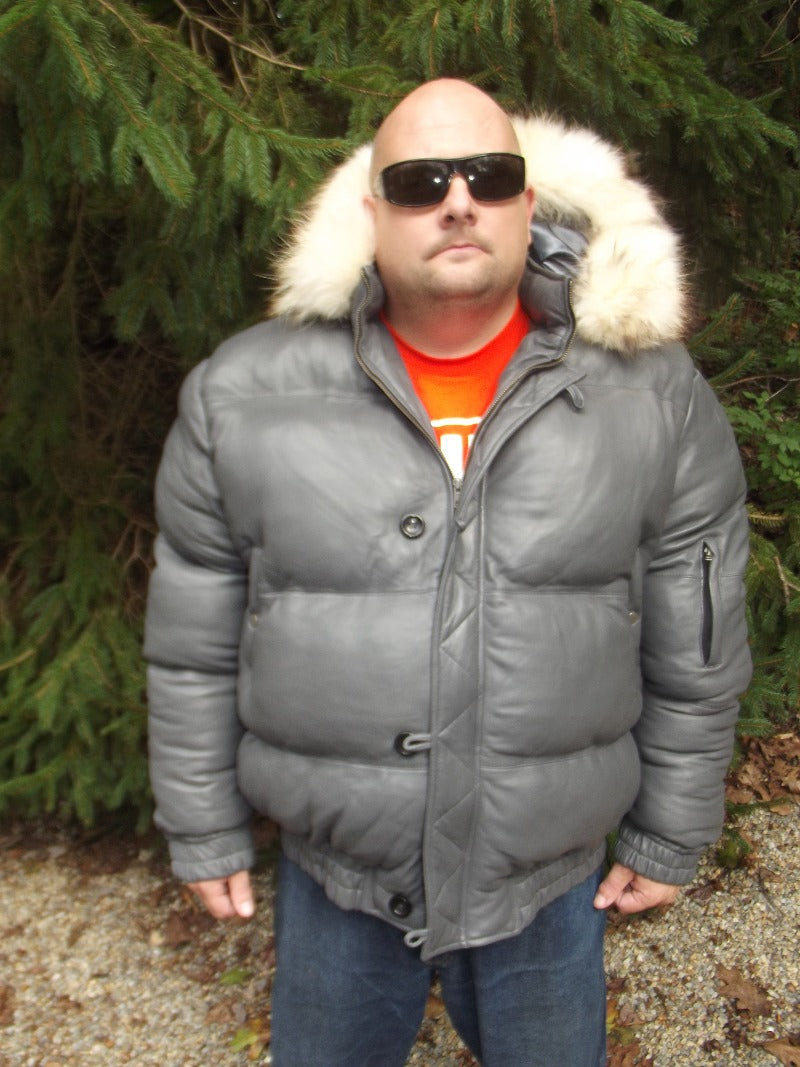 Picture of a model wearing our Max Julian Leather Jacket. Gray Color front view with fur lined hood down