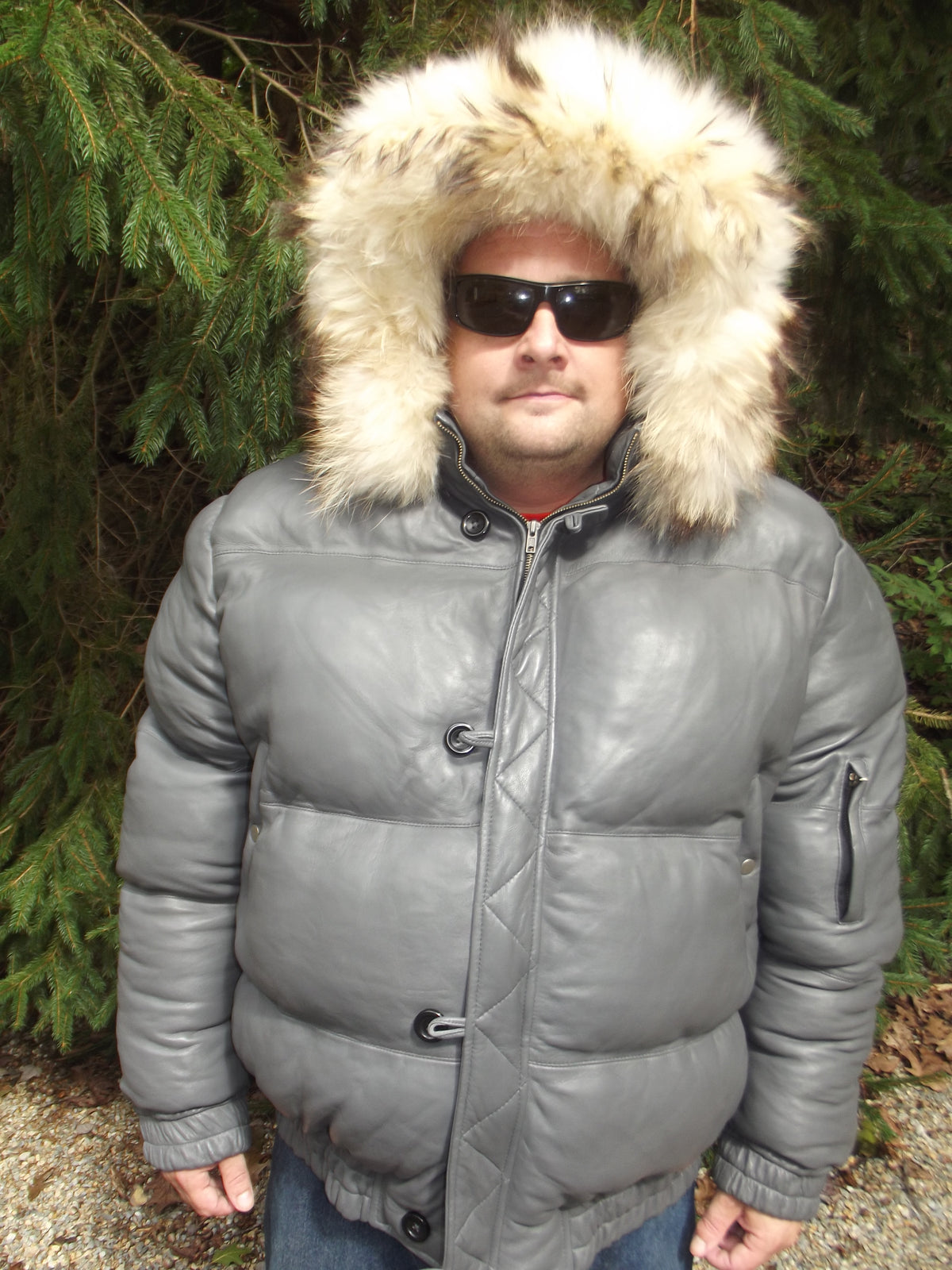 Picture of a model wearing our Max Julian Leather Jacket. Gray Color front view with fur lined hood up.