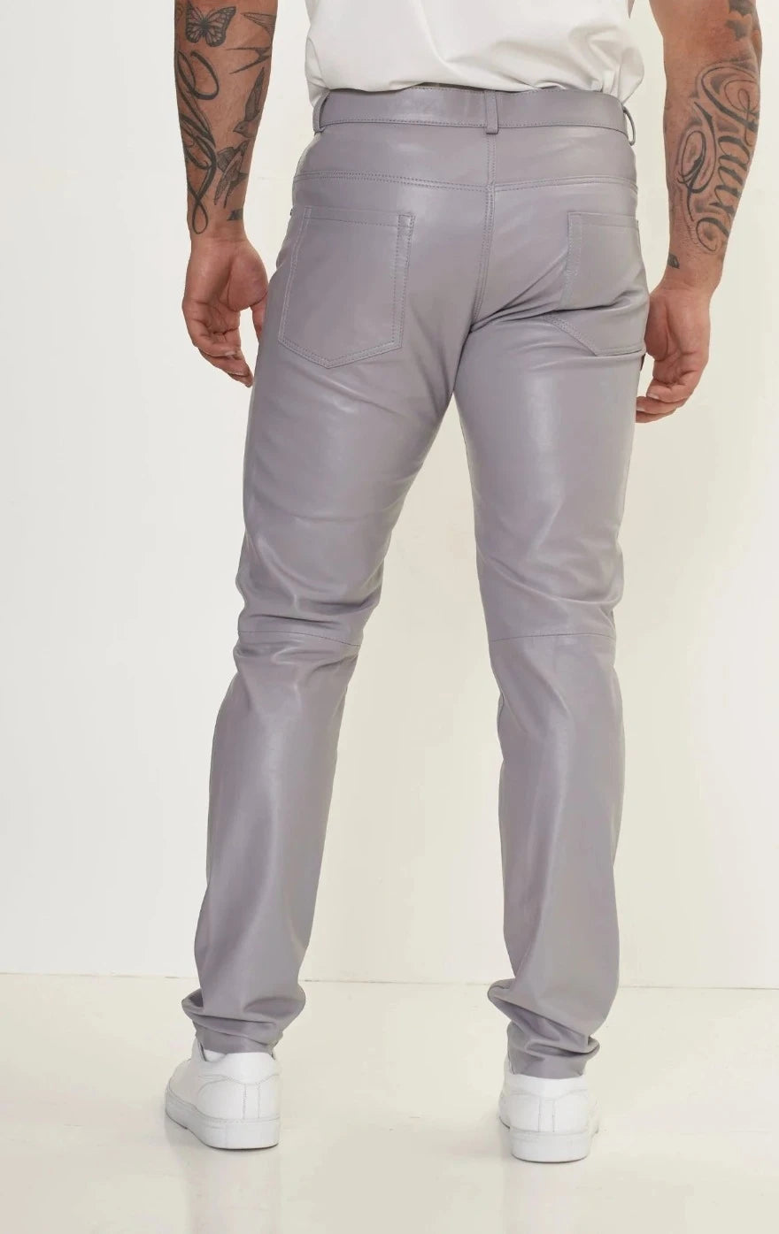 Picture of a model wearing our light grey leather pants. Back view.