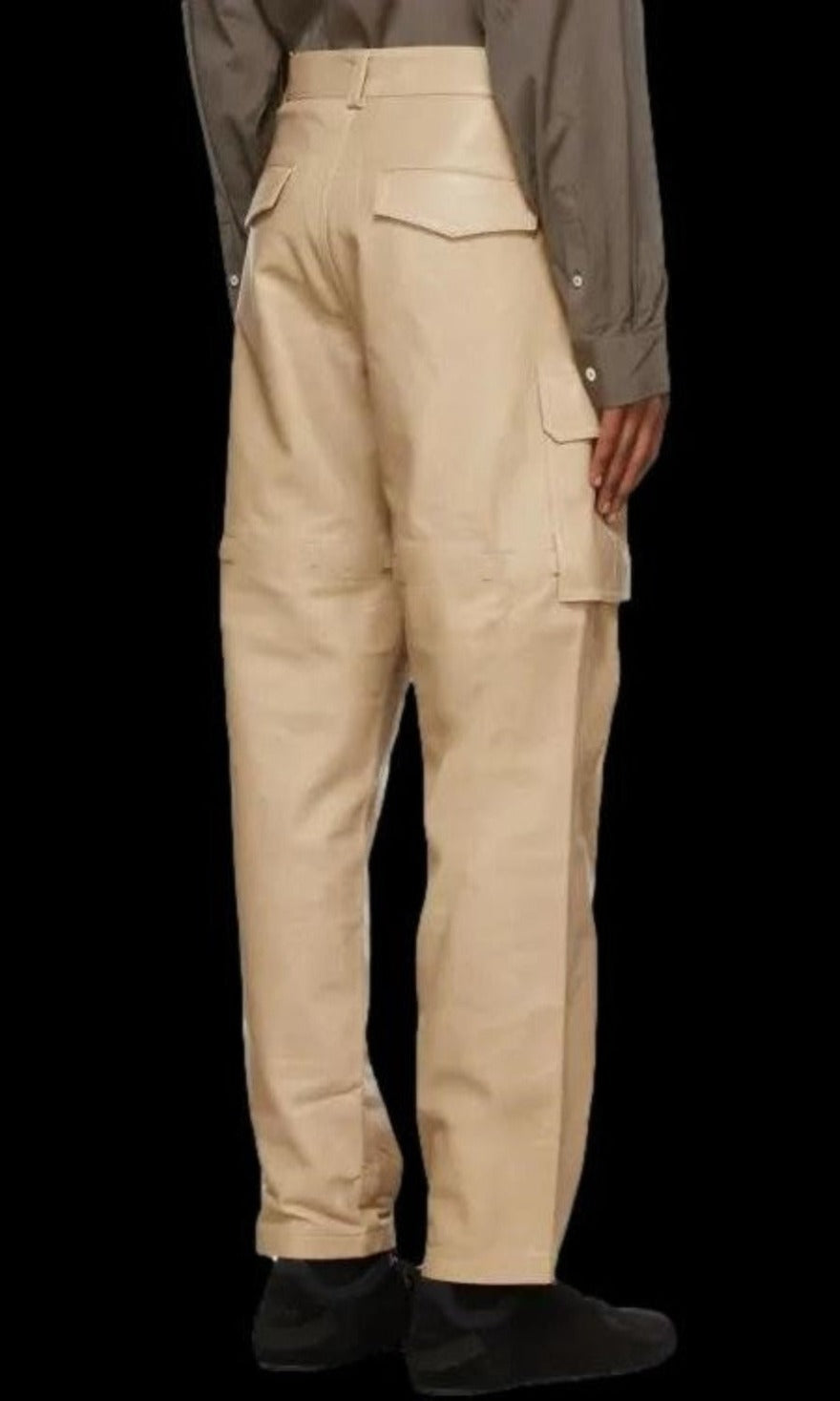 Picture of a model wearing our white leather cargo pants, back view. with black background for contrast.