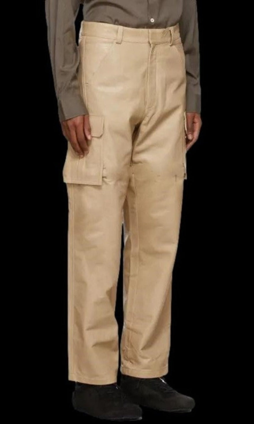 Picture of a model wearing our white leather cargo pants, side view. with black background for contrast.