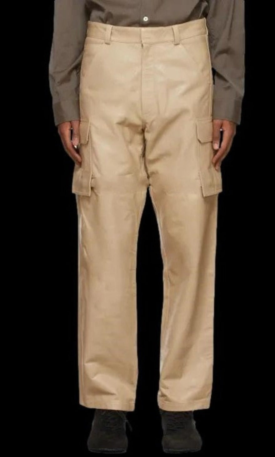 Picture of a model wearing our white leather cargo pants, front view. with black background for contrast.