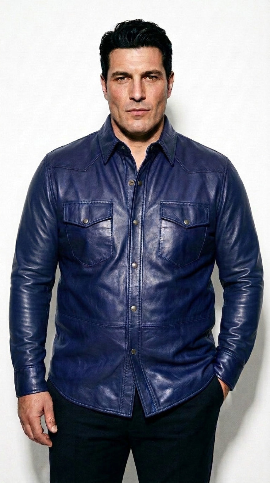 A man wearing our blue leather button-up shirt  with two chest pockets, paired with black pants, standing against a white studio background.