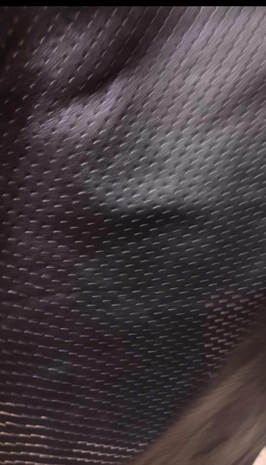 Close up picture of perforated black leather showing the small ventilation holes