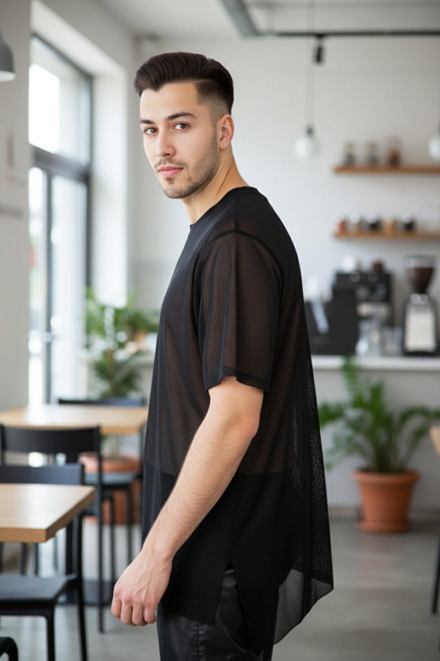 Man wearing a black Mens Perforated Leather Tee Shirt in a modern cafe setting
