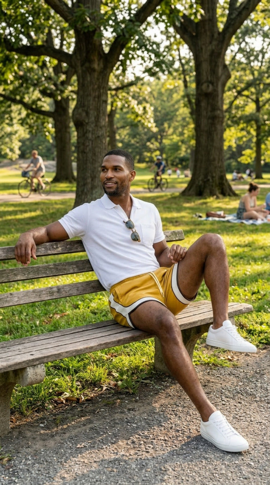 Picture of a man wearing our Yellow Men's Leather Shorts with Contrast Side Stripe and a white polo shirt,  sitting on a park bench.