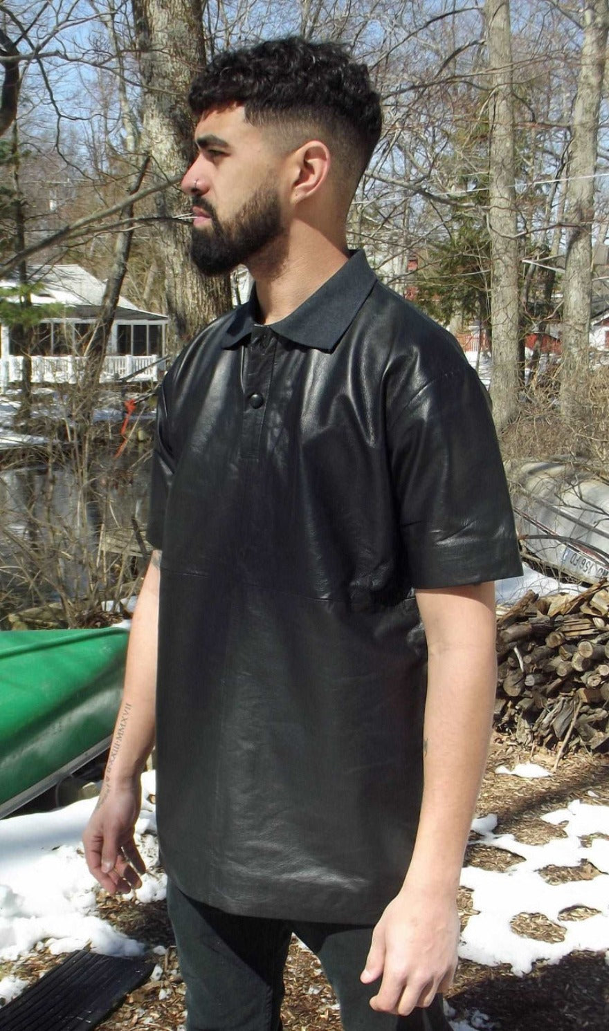 Picture of a model wearing a Mens leather polo shirt, black color, side view