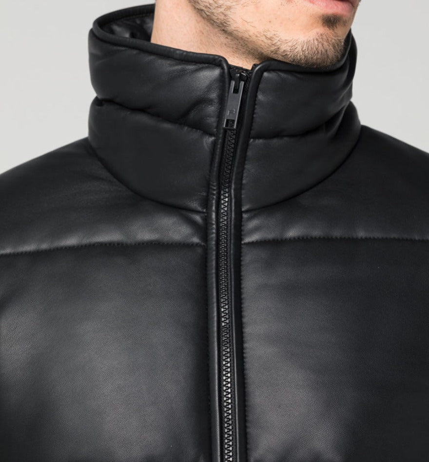 Picture of a mens quilted leather jacket in black with a wide square pattern, close up view.